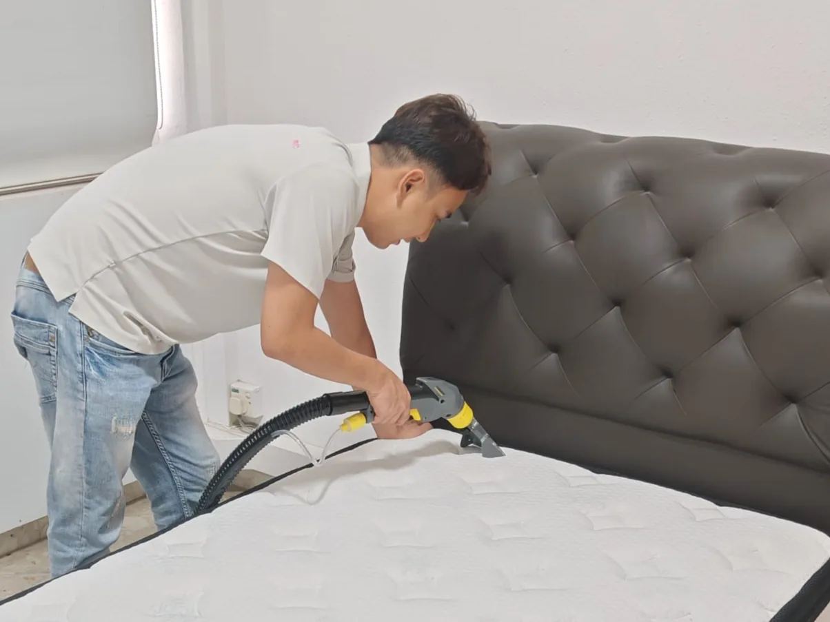 Mattress cleaning in front of a tufted grey headboard
