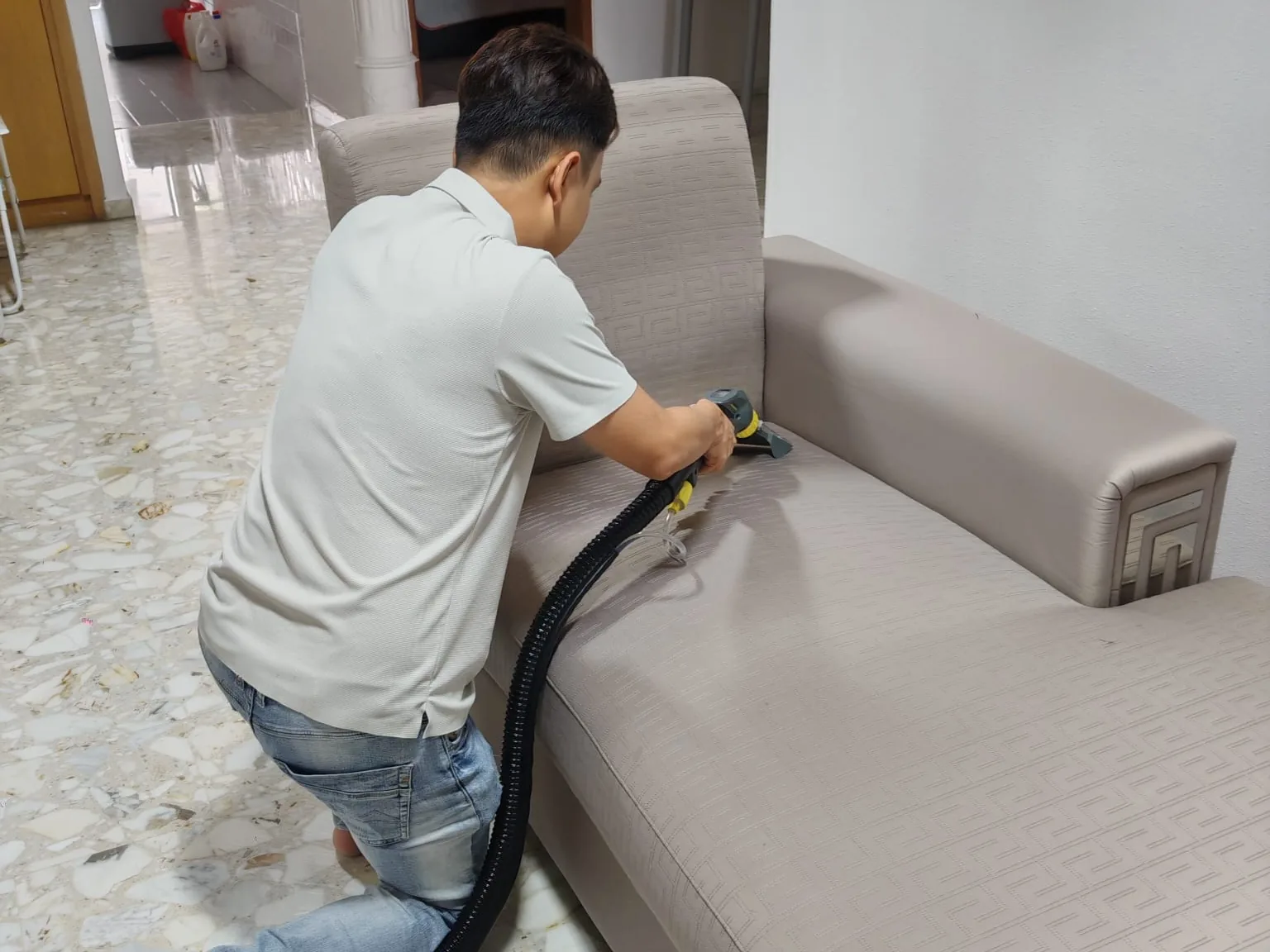 Technician steam cleaning a taupe fabric sofa
